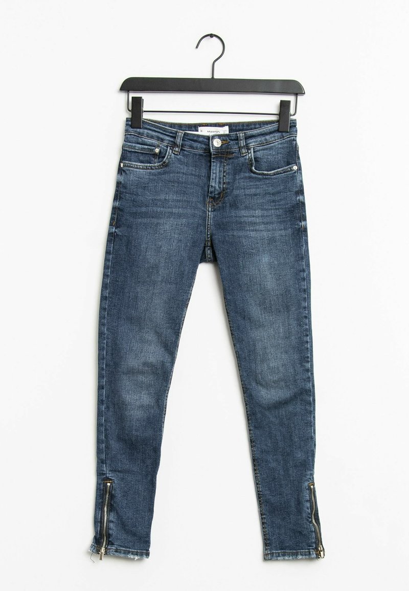 Jean skinny en denim bleu avec poches avant et arrière, ourlets zippés, suspendu à un cintre noir sur fond blanc.