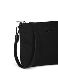 Černá plátěná taška s hladkým koženým popruhem, která má zipové uzavření a vytlačené logo na přední straně. Strukturovaný obdélníkový tvar.