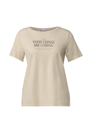 T-shirt beige à manches courtes en tissu doux, avec un col rond et un impression de texte à l'avant en gris foncé. Coupe ample avec des coutures latérales.