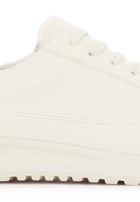 Baskets blanches avec une tige texturée en fourrure douce, dotées d'une semelle en caoutchouc à motif de crampons et d'une fermeture traditionnelle à lacets.