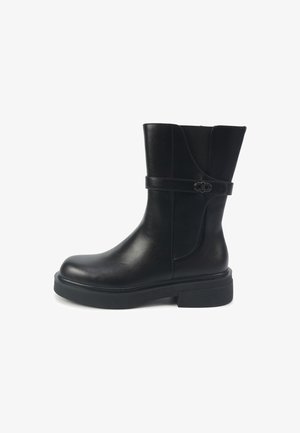 Must nahast pahkluu saabas ümmarguse varbaosaga, siledapindilise tekstuuriga ja külje peal hõbedase pandlaga rihmaga. Paks must tald.