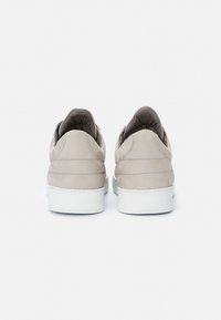 Beige semišové tenisky s nízkým střihem, bílé gumové podrážky a prošitím na patě a po stranách.
