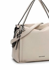 Peach-colored handbag in textured material with black accents, structured shape, dual handles, and a decorative zipper pull.