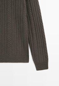 Dark gray cable-knit sweater with a textured pattern, ribbed cuffs, and hem. Features a crew neckline and soft fabric.