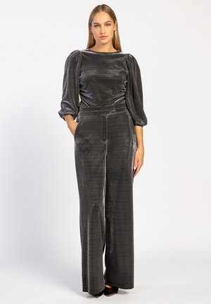 Grijze, gestructureerde jumpsuit met lange mouwen, een getailleerde taille en brede pijpen. Voorzien van een subtiele glans en zijzakken.