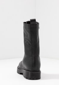 Svart läderankelboot med en texturerad finish, slät över skaftet och en räfflad gummisula. Inkluderar en dragrem för enkel påtagning.