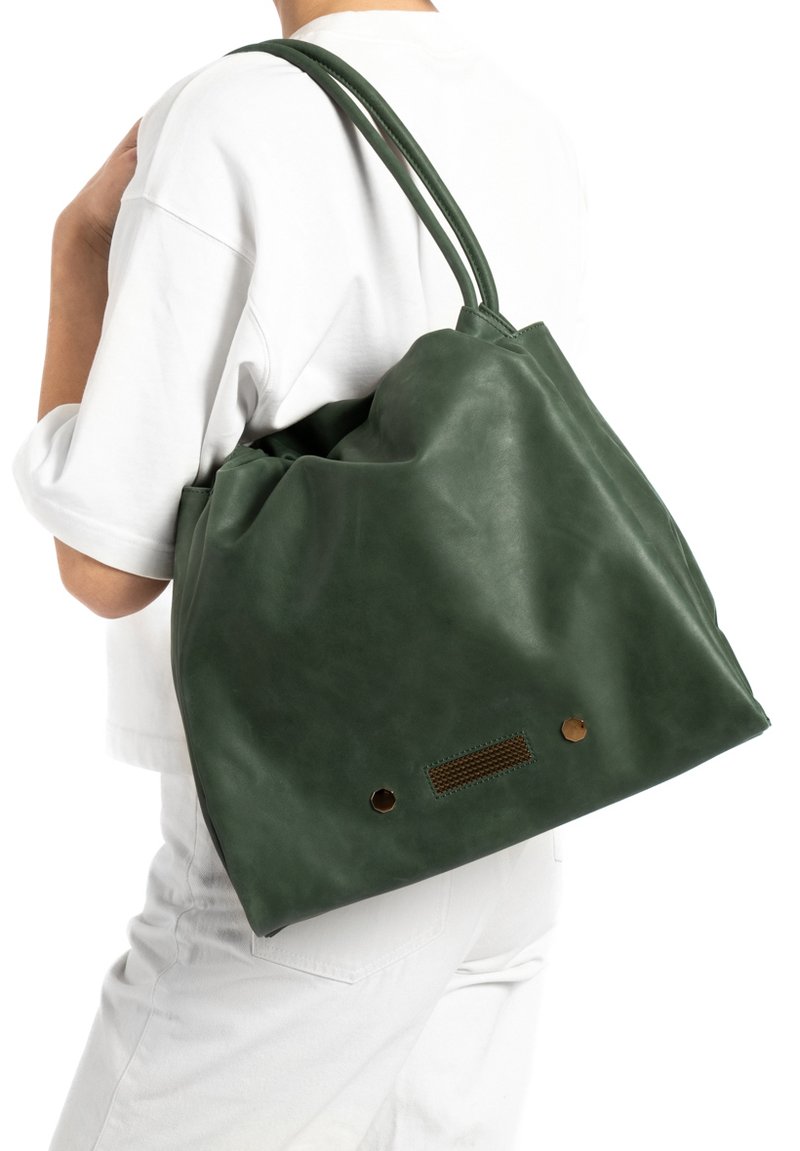 Groene leren draagtas met een slouchy ontwerp, voorzien van een gladde textuur, ronde vorm en bronzen hardware accenten.