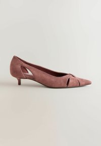 Mauve ruskind pumps med spids tå, lav hæl og udskæringsdetaljer på tå og side, set fra venstre profil mod en neutral baggrund.