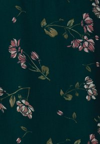 Tessuto floreale con uno sfondo verde scuro, caratterizzato da fiori rosa e bianchi e foglie verdi, che trasmette un design morbido e testurizzato.
