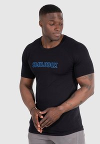 Camiseta deportiva de manga corta negra con texto azul "SMILODOX" en el frente, que presenta un corte ajustado y un material suave de mezcla de algodón.
