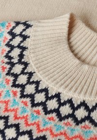 Suéter de punto con un amplio cuello de canalé color crema, decorado con formas geométricas en tonos navy, coral y azul sobre un fondo crema.