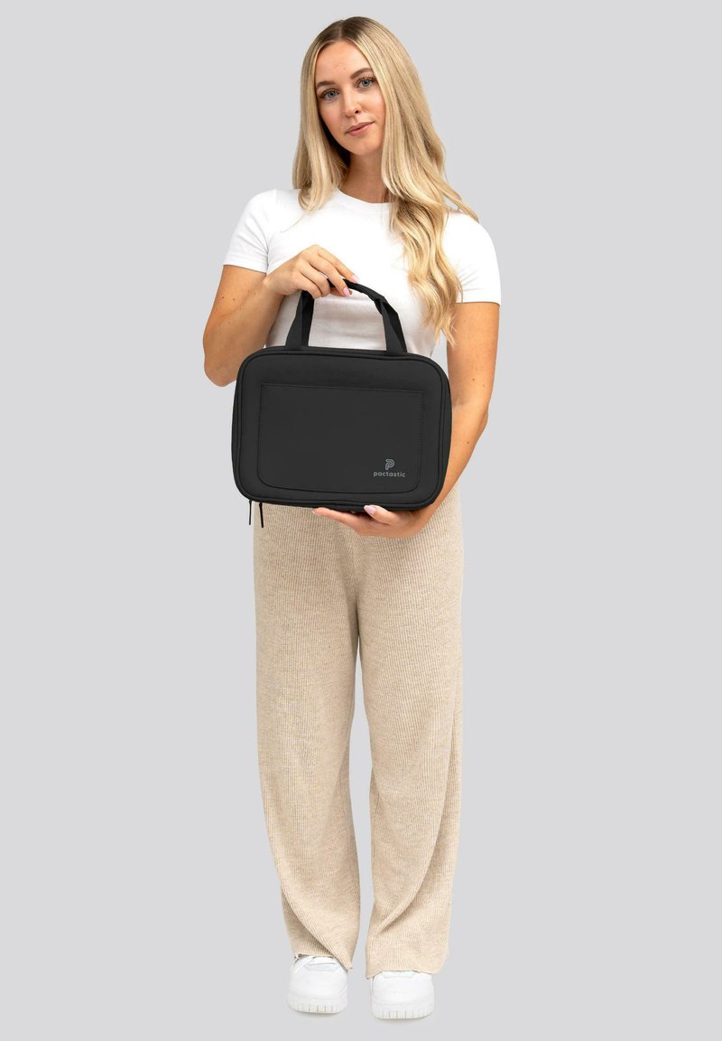 Borsa in tessuto nero con struttura imbottita, chiusura con zip e due manici; presenta un pannello frontale con logo.