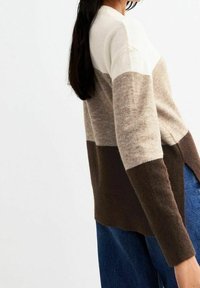 Gebreide trui met een kleurblokontwerp in crème, beige en bruin. Licht oversized pasvorm met lange mouwen en zijwaartse splitsingen.