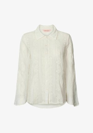 Blusa bianca a maniche lunghe con chiusura a bottoni, tessuto strutturato con righe verticali e accenti di ricamo floreale sul davanti.