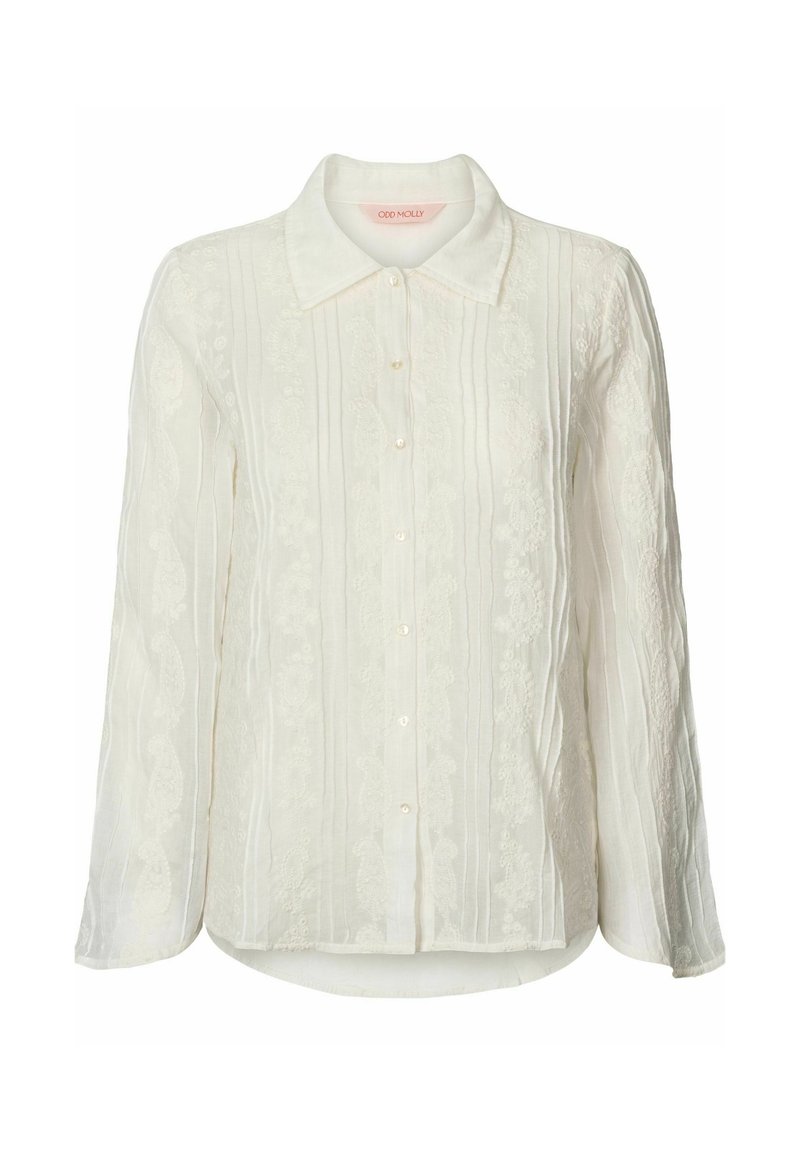 Chemisier blanc à manches longues avec fermeture à boutons, tissu texturé avec des rayures verticales et des accents de broderie florale à l'avant.