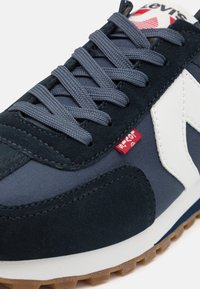 Sötétkék sneaker, velúr és textil felsőrésszel, szürke fűzőkkel, fehér részletekkel és piros logócímkével. Gumi talp tapadásmintával.