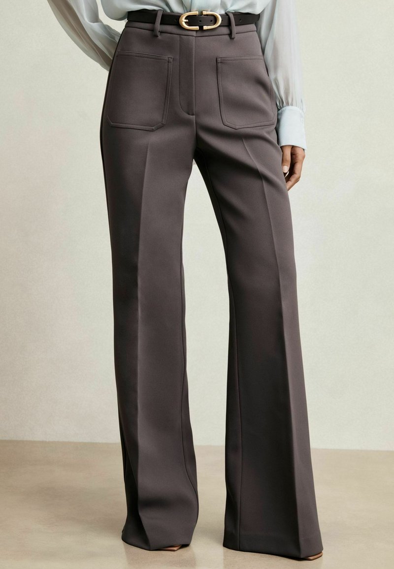 Pantaloni a gamba larga su misura in tessuto grigio scuro, con tasche frontali e una cintura con fibbia dorata, rifiniti con una texture liscia.