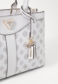 Borsa bianca realizzata in materiale testurizzato, con un logo triangolare, charm decorativi e un motivo sottile. Accentuata da dettagli in oro.
