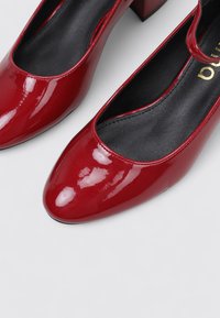 Chaussures à talons hauts en cuir verni rouge avec un design à bout arrondi. L'intérieur est doté d'une doublure noire. Talon bloc pour plus de stabilité.