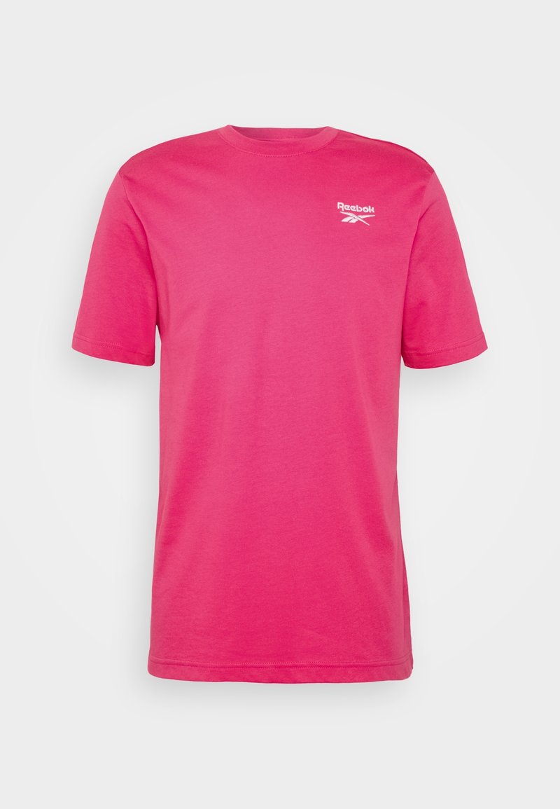 Camiseta de algodón rosa con mangas cortas y cuello redondo. Presenta un pequeño logo blanco de Reebok en el pecho. Diseño sencillo y sin adornos.