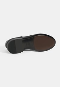 Zwarte leren schoenzool met een gladde bruine middenstuk, een gestructureerde rubberen onderkant voor grip en een afgerond hakontwerp.