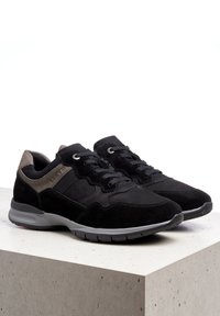 Černé semišové tenisky s texturovaným svrchním dílem, šedými akcenty a lehkou podrážkou. Obsahují tkaničky a polstrovaný límec pro pohodlí.