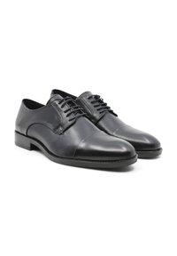 Scarpe eleganti in pelle nera con finitura liscia, punta arrotondata, design con lacci e tacco basso impilato. Dettagli di cucitura sottili lungo le cuciture.