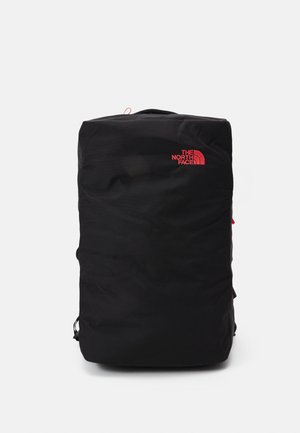 Sac à dos rectangulaire noir avec logo The North Face rouge sur la partie supérieure avant, posé debout sur un fond blanc.