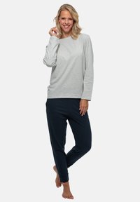 Grå långärmad topp och marinblå tapered byxor i mjukt tyg. Toppen har en rundad halsringning; byxorna har ett elastiskt midjeband med manschetter.
