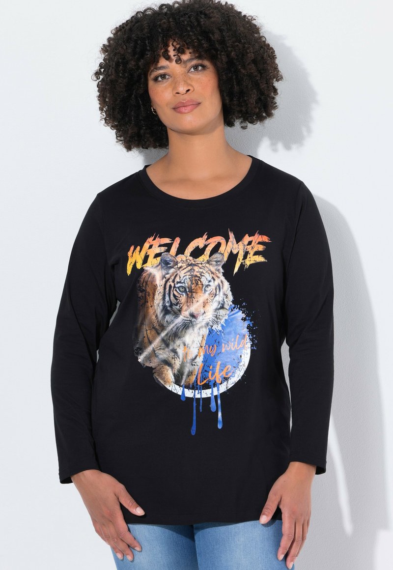 Camiseta negra de manga larga con un gráfico de un tigre y el texto "BIENVENIDO a mi vida salvaje" en colores vibrantes sobre un diseño circular.