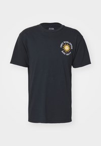 Svart bomullst-skjorte med korte ermer og rund hals. Foran er det et grafisk trykk med en sol-design og teksten: "Obey Worldwide Rise Above."