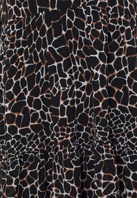 Tissu noir présentant un motif imprimé de girafe avec des formes irrégulières dans des nuances de marron et de blanc. Texturé avec des accents froncés.