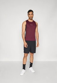 Tamsiai raudonas be rankovių sportinis marškinėlis su juodais akcentais, derinamas su juodais šortais. Balti sportbačiai ir juodos kojinės užbaigia aprangą.