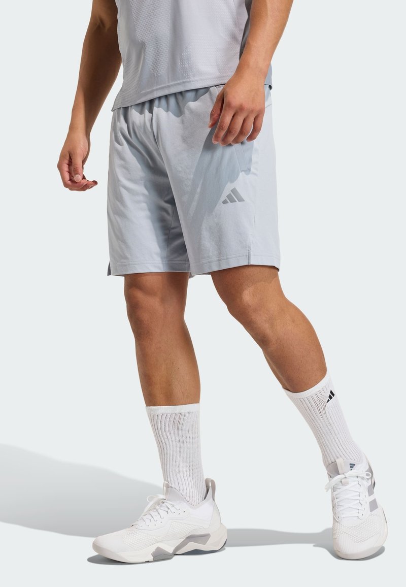 Light grey athletic shorts with an elastic waistband and side pockets. Paired with white sneakers and ribbed white socks.