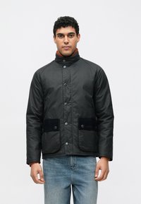 Fekete, bélelt dzseki magas gallérral, patentgombokkal, két elülső zsebbel, fekete velúr részletekkel, rozsdaszínű garbó fölött viselve.