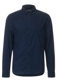Košile s dlouhým rukávem na knoflíky v námořnicky modré látce s texturovaným povrchem, s límečkem do špičky a malou nášivkou s logem na levé části hrudi.