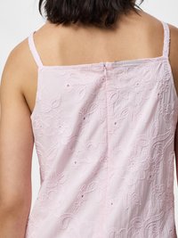 Personne portant une robe rose pâle sans manches avec broderie florale, vue de dos avec une fermeture éclair centrale visible.
