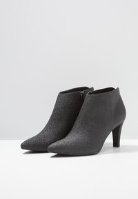 Stivali alla caviglia neri con glitter, dalla punta affilata e un tacco sottile, dotati di una chiusura con zip sul lato e una texture liscia.