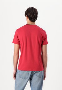 Rød bomulls T-skjorte med korte ermer og rund hals, med et enkelt design og en avslappet passform. Kombinert med lyseblå jeans.