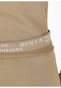 Beiger, gerippter Stoffbund mit weißem Logo "SWEDEMAG", versehen mit Pflegehinweisen und Größenetikett. Weiche Textur, elastische Passform.