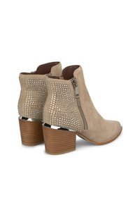 Bottines beiges en daim avec un dos texturé de strass et un accent en métal argenté. Elles sont dotées d'une fermeture éclair et d'un talon empilé.