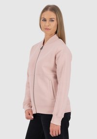 Giacca bomber rosa con zip, dotata di colletto e polsini a coste, caratterizzata da due tasche laterali e una texture di tessuto liscia.