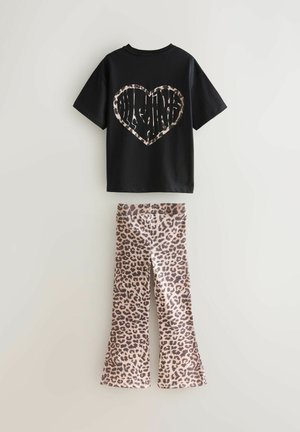 Melns īsroku T-krekls ar leoparddrukas sirds dizainu uz muguras, kombinēts ar leoparddrukas zvana biksēm brūnos toņos.