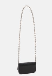 Borsa a spalla rettangolare nera con patta con logo in rilievo e tracolla a catena argentata appesa su sfondo bianco.
