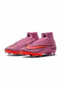 Un paio di scarpini da calcio alti rosa con suole arancioni e loghi Nike neri, progettati per il gioco su terreni compatti.