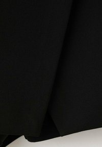 Tela negra con una textura suave y mate, presenta pliegues que crean un ligero brillo. El material parece ligero y flexible.