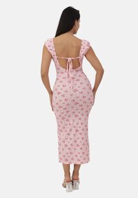 R�óżowa w kwiaty midi sukienka z falbaniastymi rękawami, odkryty tył zabezpieczony wiązaniami, dopasowany fason i gładka faktura materiału. Przezroczyste słupkowe obcasy.