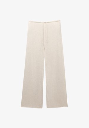 Svetlo bež široke hlače z elastiko v pasu. Pletena tekstura, sproščen kroj in polna dolžina. Brezšivni robovi na hlačah.