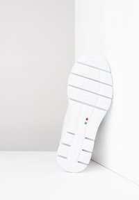 White sneaker with a textured rubber sole featuring horizontal grooves, Italian flag detail, and smooth synthetic upper.