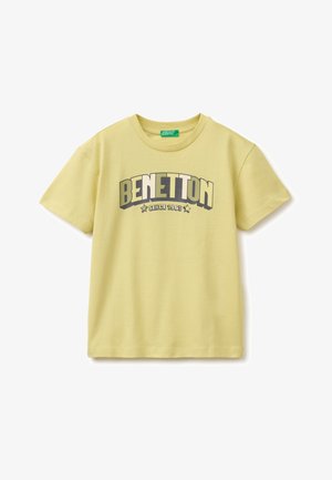 T-shirt jaune clair à manches courtes avec "BENETTON" en grandes lettres majuscules et "SINCE 1965" en dessous, accentué par deux étoiles.